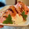 Burrata cheese topped with tomato shave ice and drizzled with balsamic glaze, olive oil and flaky salt. Garnished with sprigs of basil.