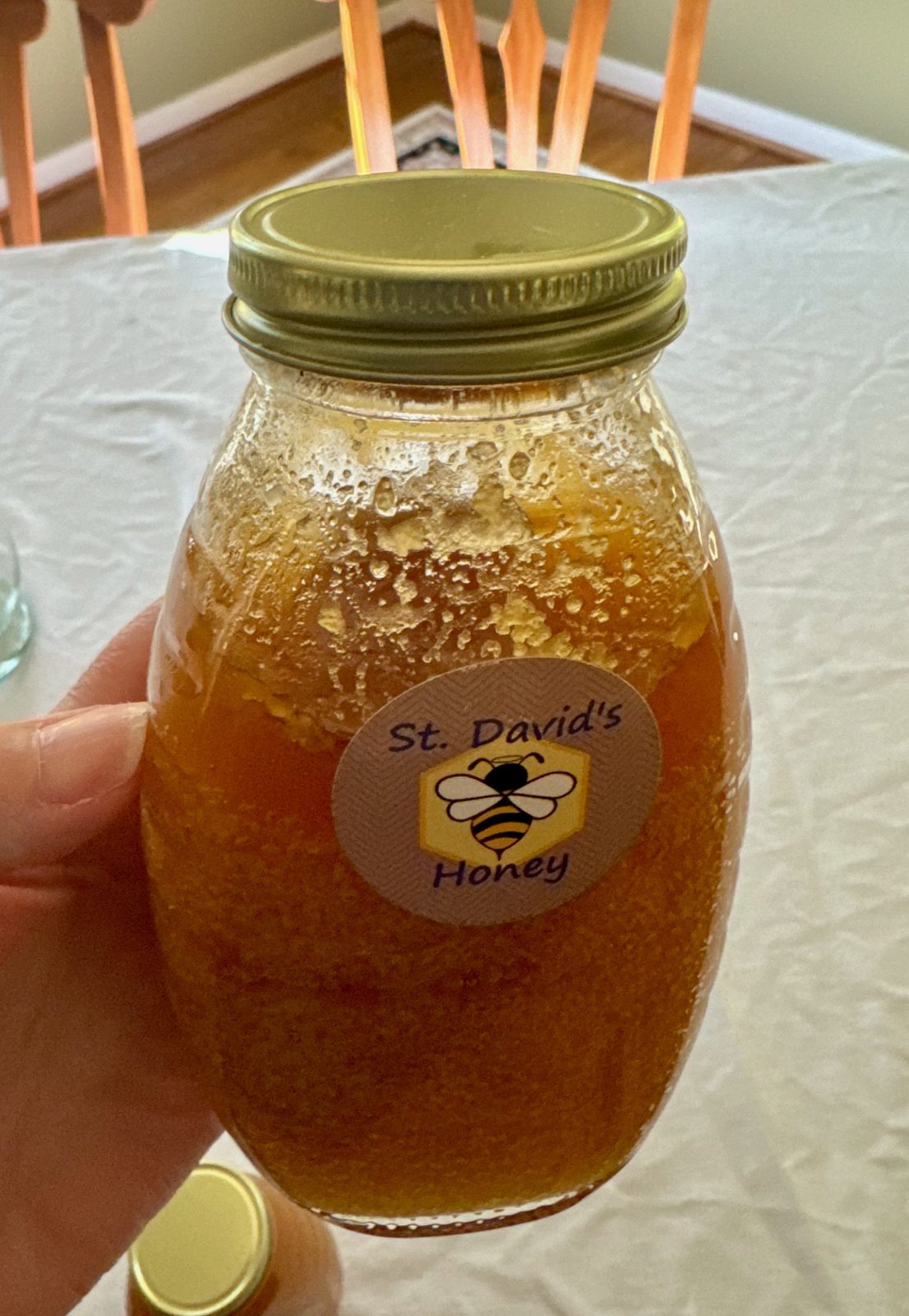 Crystallized honey in a clear glass jar with gold lid and sticker that reads St. David's Honey.