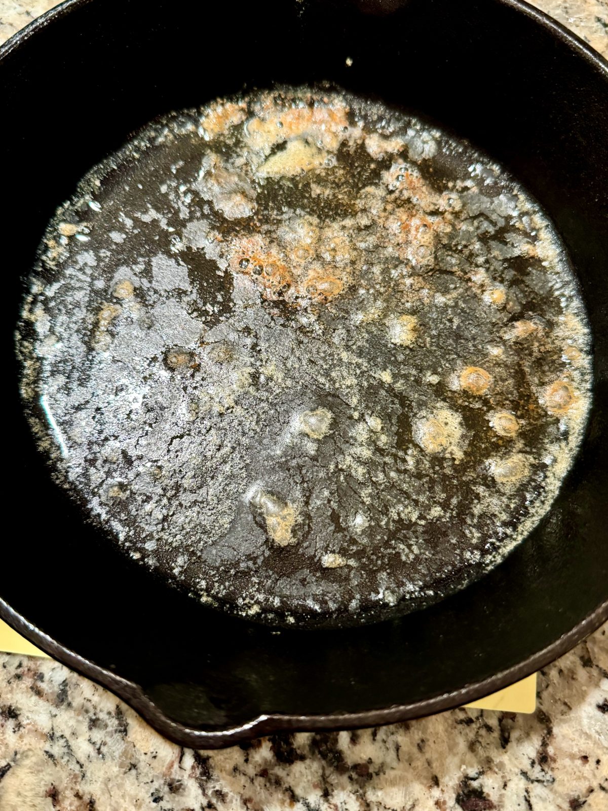 Recipe Photo for making sourdough cornbread showing melted browned butter in cast iron skillet