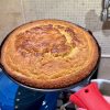 Recipe Photo showing golden brown baked sourdough cornbread in 8 inch cast iron skillet with red heat protector on handle.