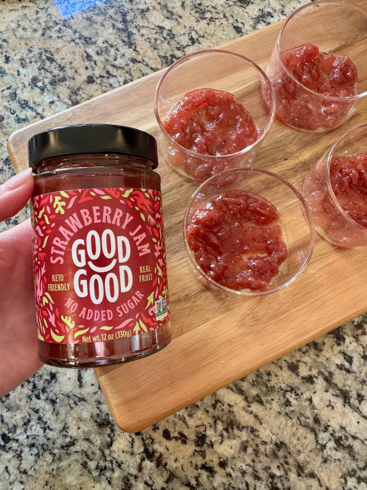 Jar of Good Good Low Sugar Strawberry Jam. with cups each filled with a tablespoon of said jam.  To be used to make Greek Yogurt Cups recipe.
